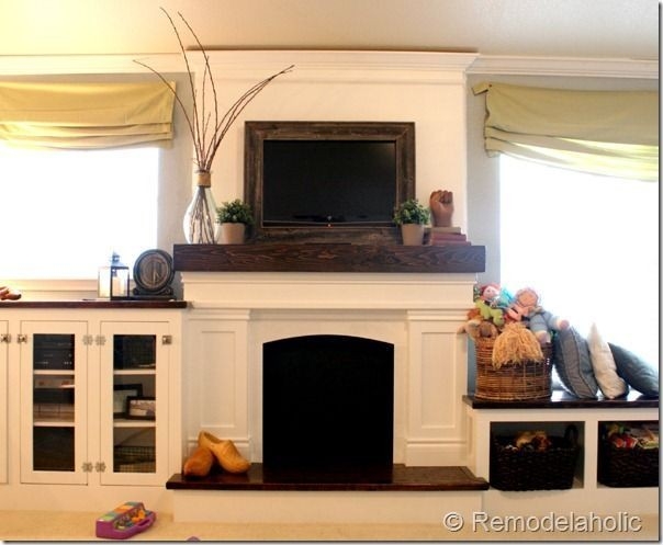image of note the framed flat screen tv, mantle styled with wood beam look above flat screen tv on fireplace mantel image